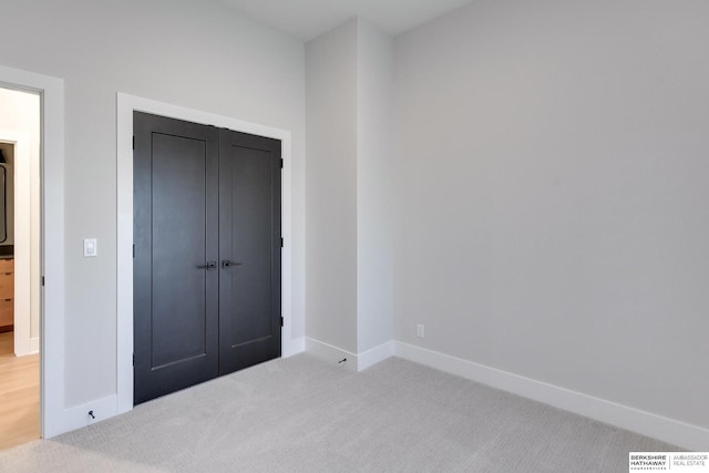 unfurnished bedroom with a closet and light colored carpet