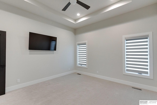 carpeted empty room with a tray ceiling and ceiling fan