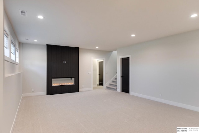 spare room featuring a large fireplace and light carpet