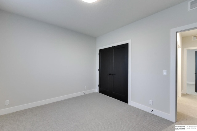 unfurnished bedroom with light carpet and a closet