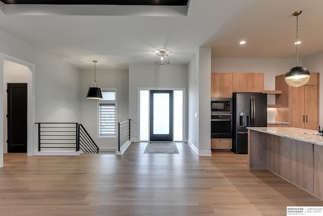 kitchen with built in microwave, light stone counters, light hardwood / wood-style flooring, refrigerator with ice dispenser, and black oven