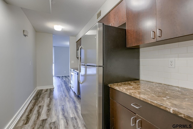 kitchen featuring stainless steel refrigerator, tasteful backsplash, light hardwood / wood-style flooring, white electric stove, and stone countertops