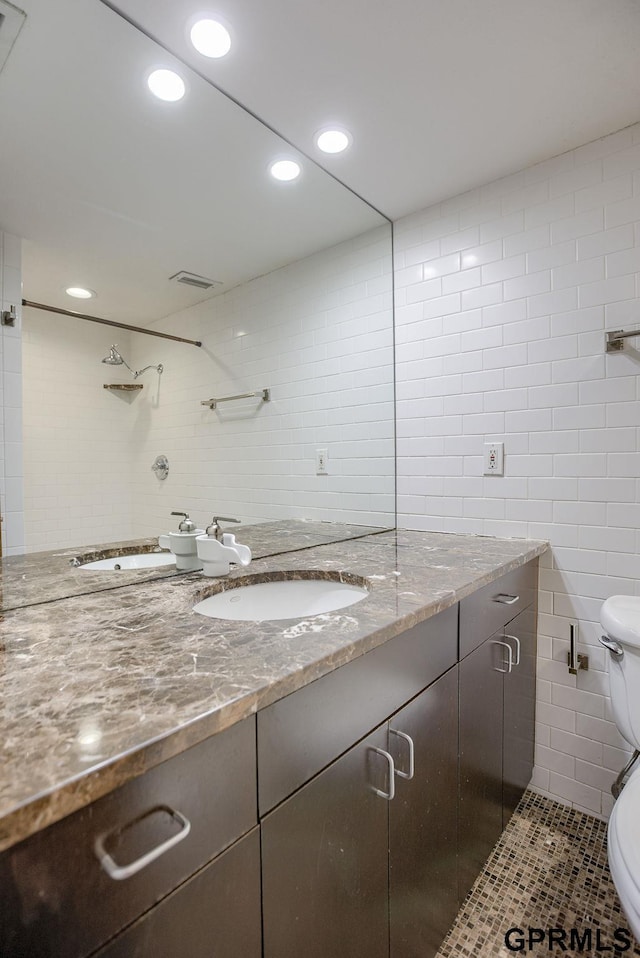 bathroom featuring tile patterned flooring, vanity, toilet, and tile walls