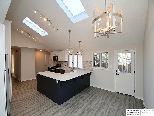 kitchen with backsplash, white cabinets, kitchen peninsula, a breakfast bar area, and a chandelier