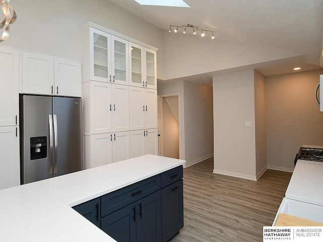 kitchen featuring a skylight, stainless steel fridge, stove, and white cabinets