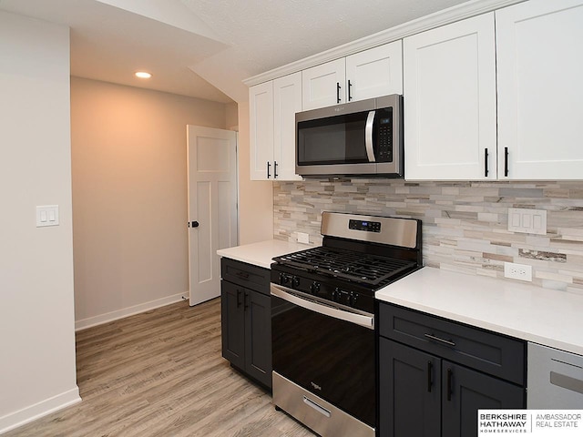 kitchen featuring lofted ceiling, decorative backsplash, light hardwood / wood-style floors, white cabinetry, and stainless steel appliances