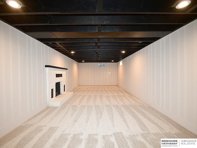 basement with light carpet and a fireplace