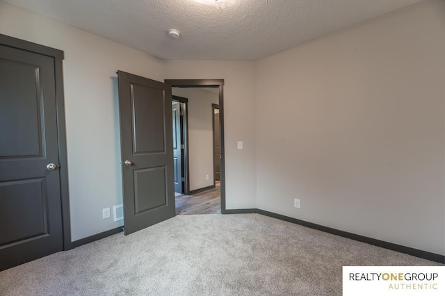 unfurnished bedroom with light colored carpet and a textured ceiling