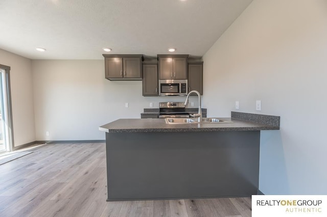 kitchen with kitchen peninsula, sink, and light hardwood / wood-style floors