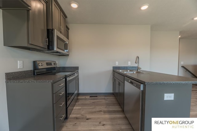 kitchen with kitchen peninsula, sink, stainless steel appliances, and light hardwood / wood-style floors