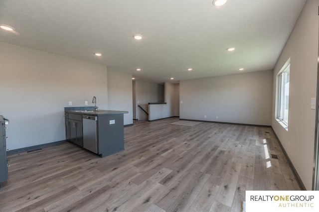 kitchen featuring dishwasher, kitchen peninsula, light hardwood / wood-style flooring, and sink