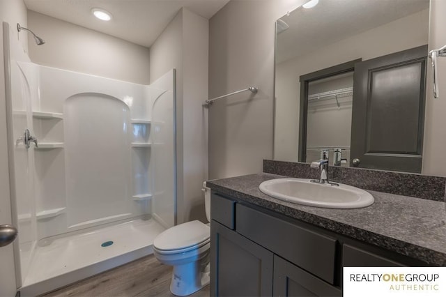 bathroom with hardwood / wood-style flooring, vanity, toilet, and walk in shower