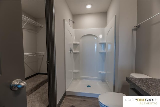 bathroom with hardwood / wood-style flooring, toilet, vanity, and walk in shower