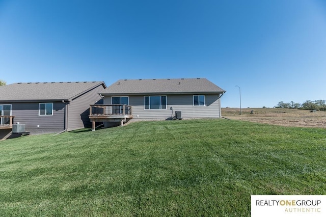 rear view of property with a deck, cooling unit, and a lawn