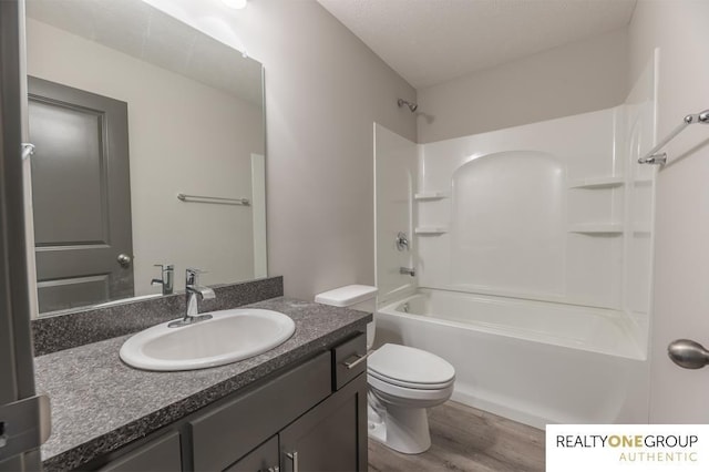 full bathroom with wood-type flooring, a textured ceiling, toilet, vanity, and shower / bathtub combination