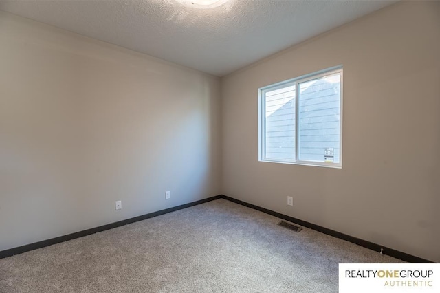 empty room with carpet and a textured ceiling