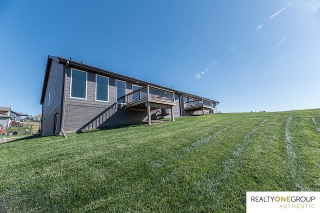 back of property with a lawn and a wooden deck