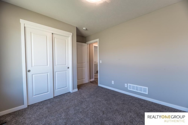 unfurnished bedroom with dark carpet and a closet