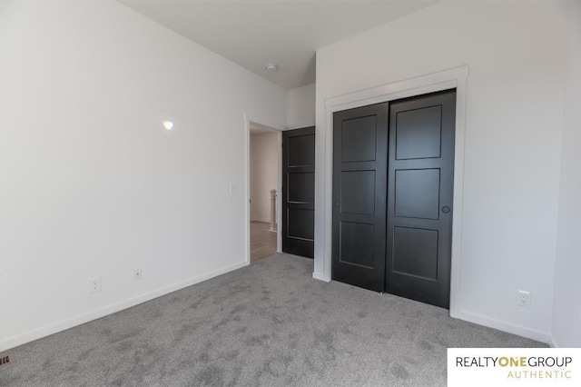 unfurnished bedroom featuring light carpet and a closet