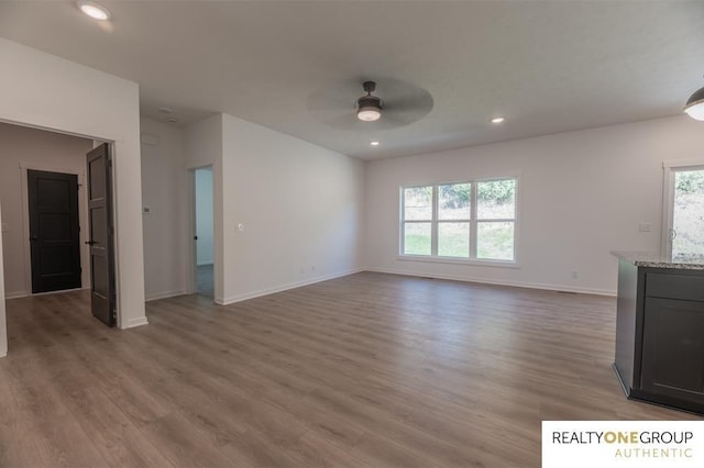 unfurnished living room featuring wood-type flooring, ceiling fan, and a healthy amount of sunlight