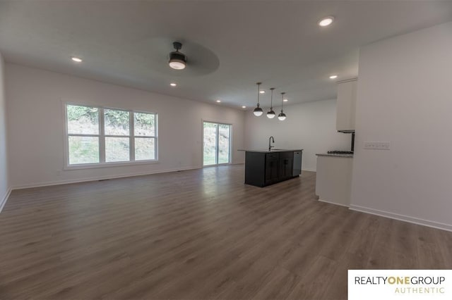 unfurnished living room with ceiling fan, sink, and dark wood-type flooring