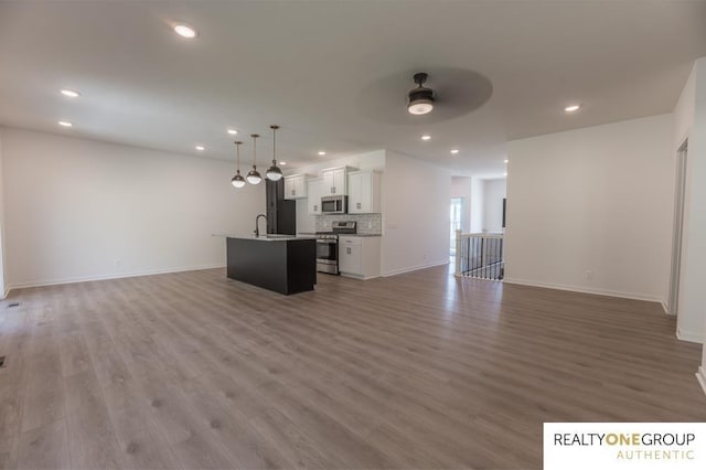 unfurnished living room featuring ceiling fan, sink, and wood-type flooring