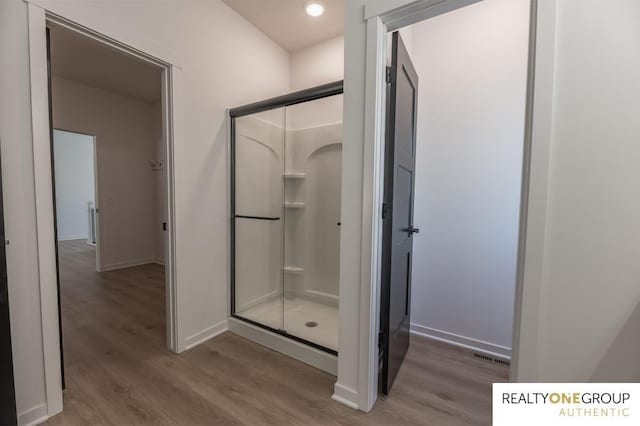 bathroom with hardwood / wood-style flooring and walk in shower