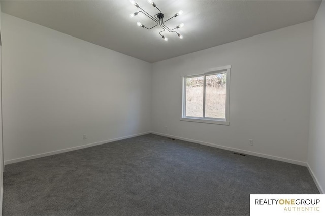 carpeted empty room featuring a chandelier