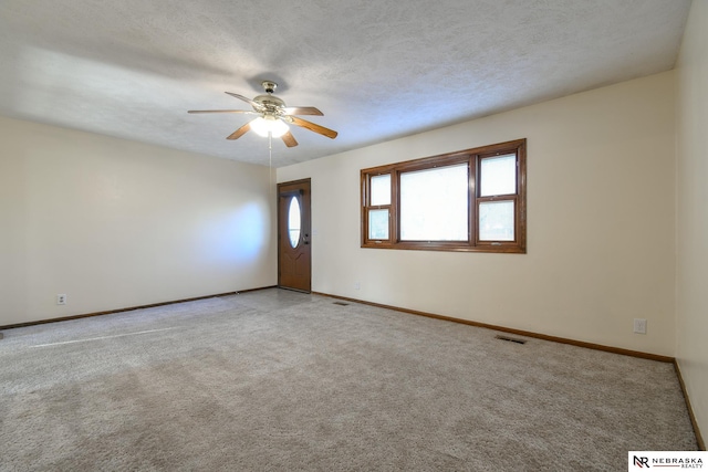 empty room with light carpet, ceiling fan, and a textured ceiling