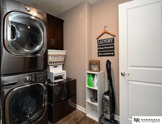 laundry room with cabinets, stacked washing maching and dryer, and a textured ceiling