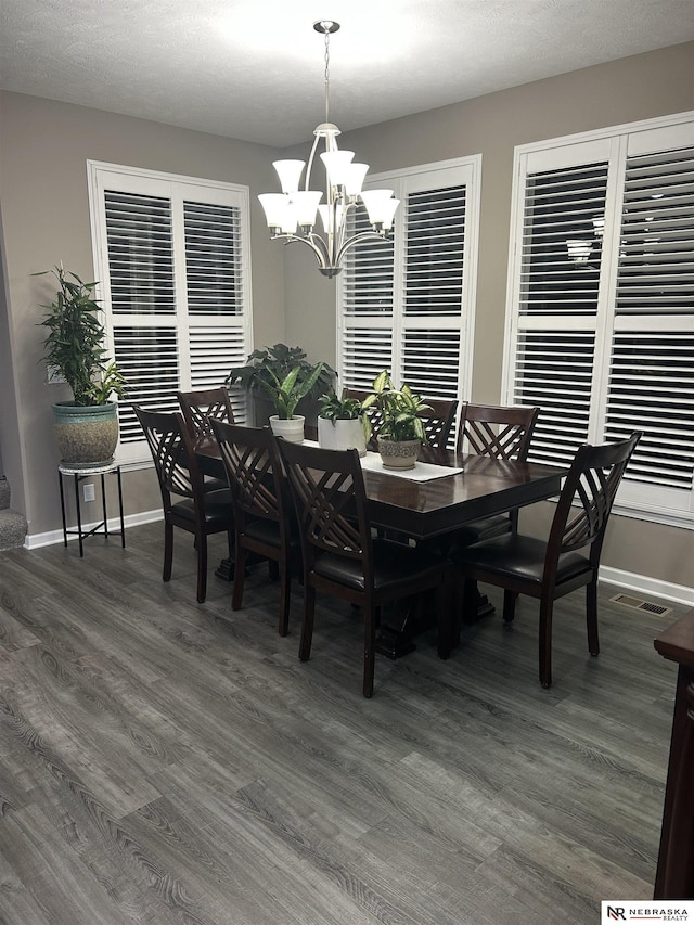 dining space with dark wood-type flooring and a chandelier