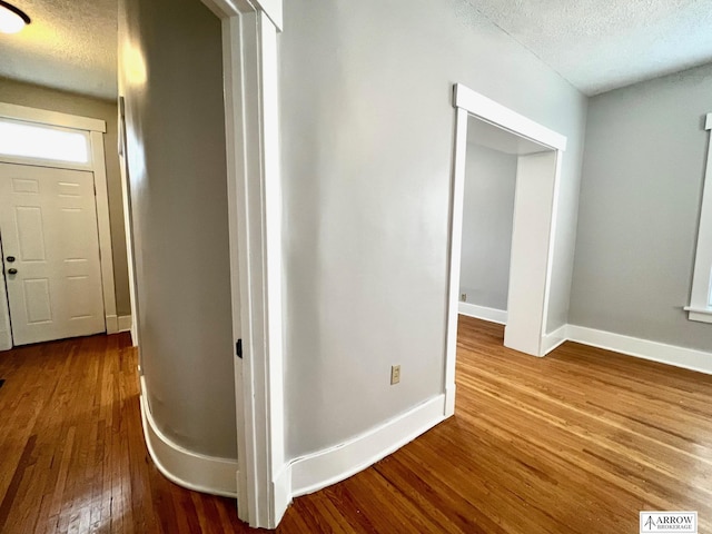 corridor with hardwood / wood-style flooring and a textured ceiling