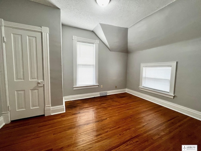 bonus room featuring a textured ceiling, vaulted ceiling, and dark wood-type flooring