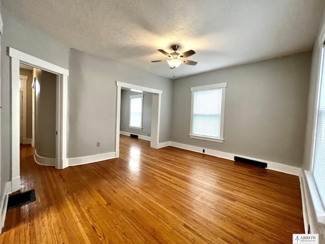 unfurnished room featuring a textured ceiling, hardwood / wood-style flooring, and ceiling fan