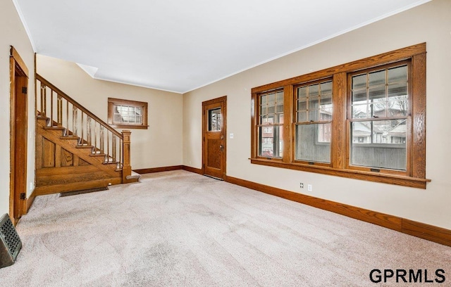 foyer entrance featuring carpet floors and ornamental molding