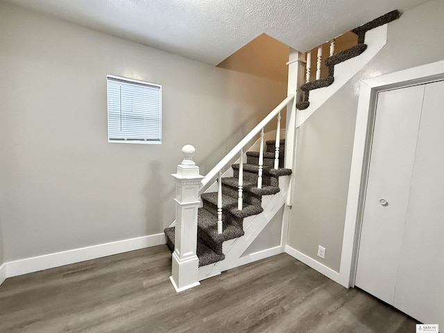 stairway with wood-type flooring and a textured ceiling