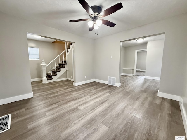 unfurnished living room with ceiling fan, hardwood / wood-style floors, and a textured ceiling