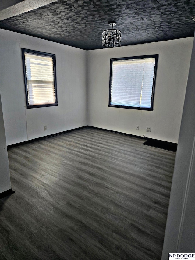 spare room with dark hardwood / wood-style flooring and a notable chandelier