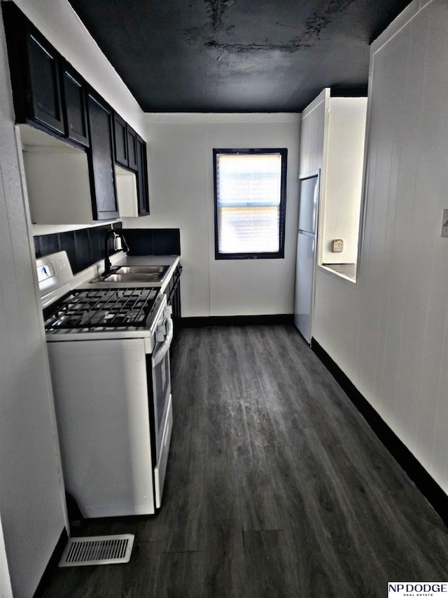 kitchen featuring white appliances, dark wood-type flooring, and sink