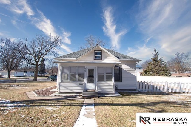 bungalow with a front lawn and a sunroom