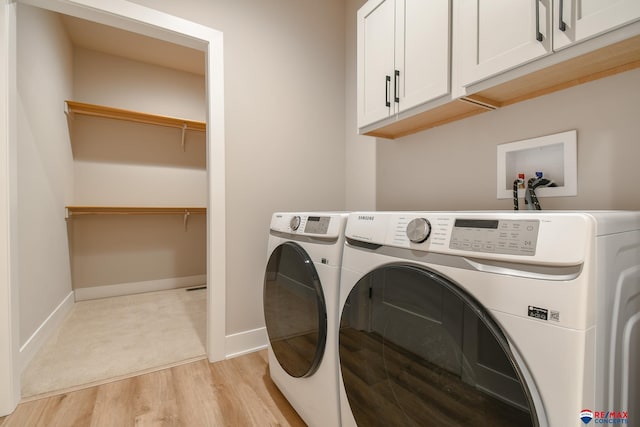 laundry area with cabinets, light hardwood / wood-style flooring, and washing machine and clothes dryer