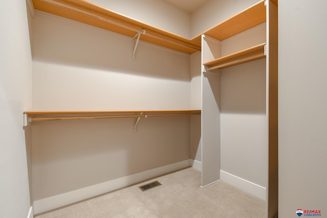 walk in closet featuring light colored carpet