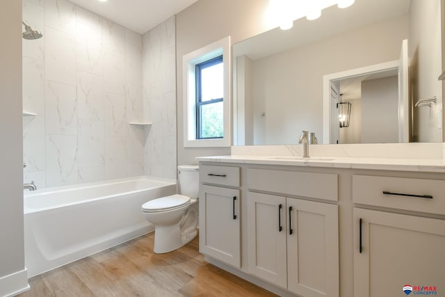 full bathroom featuring hardwood / wood-style floors, vanity, tiled shower / bath combo, and toilet