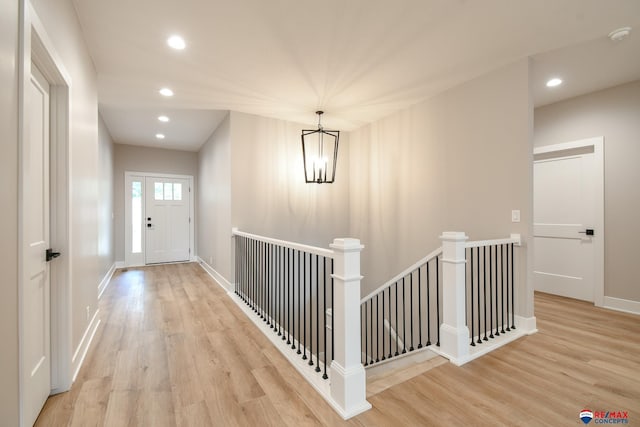 hall with light wood-type flooring and a chandelier