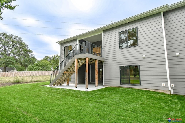 rear view of property featuring a deck, a patio area, and a lawn