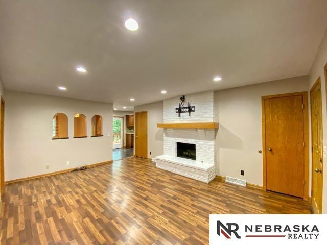 unfurnished living room featuring hardwood / wood-style flooring and a brick fireplace