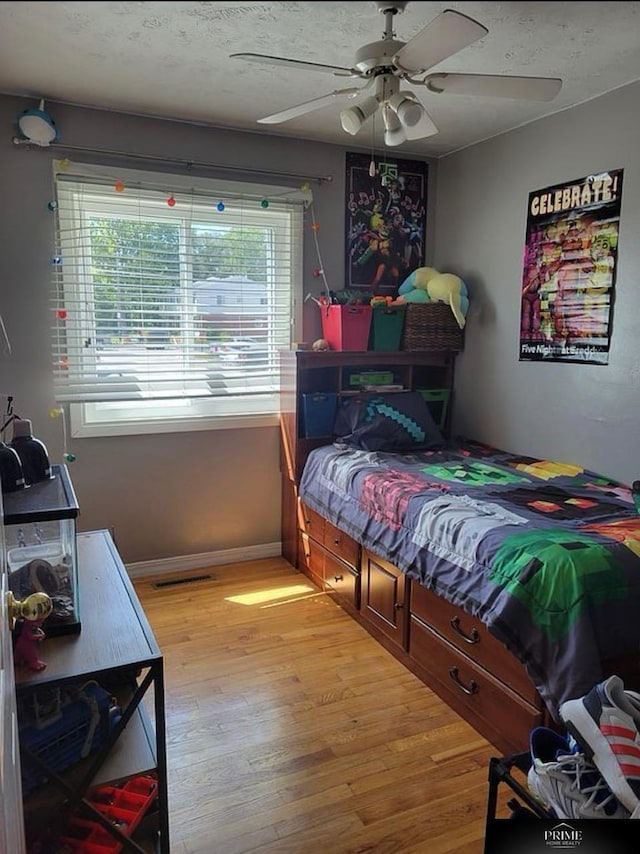 bedroom with ceiling fan, light hardwood / wood-style floors, and a textured ceiling