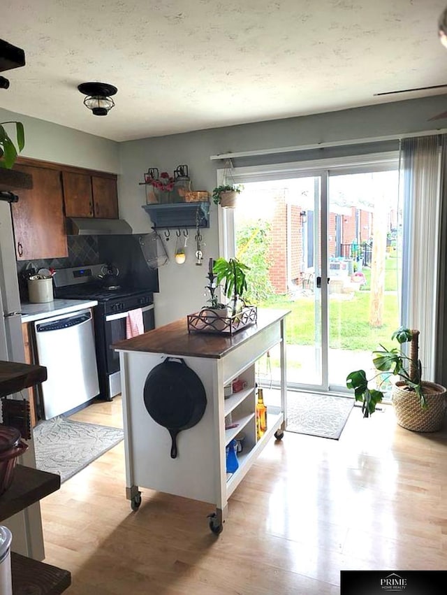 kitchen with tasteful backsplash, appliances with stainless steel finishes, and light hardwood / wood-style flooring