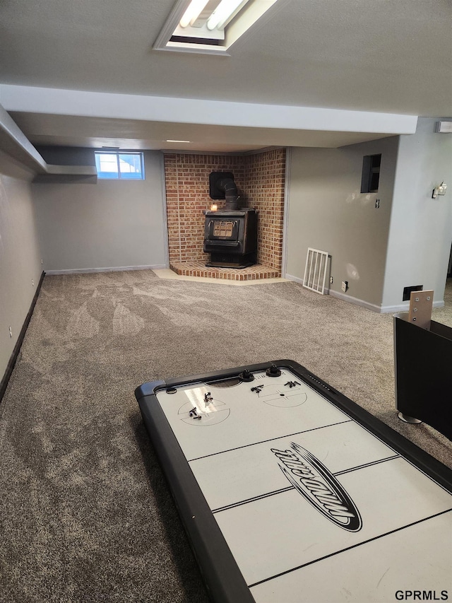 recreation room featuring a wood stove and carpet floors