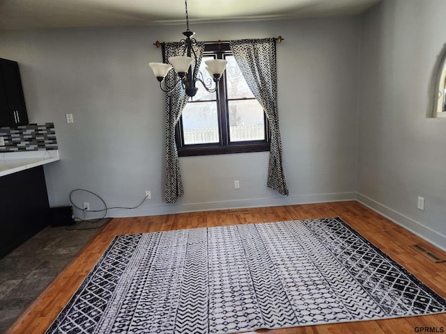 unfurnished dining area featuring hardwood / wood-style floors and an inviting chandelier